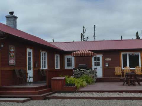 Exterior view of the lodge featuring its large wooden deck and outdoor patio furniture.