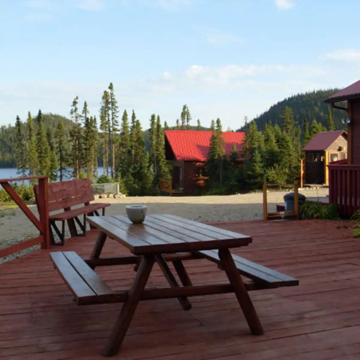 A picnic table is set up on the large wooden deck overlooking the lake.