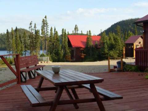 A picnic table is set up on the large wooden deck overlooking the lake.