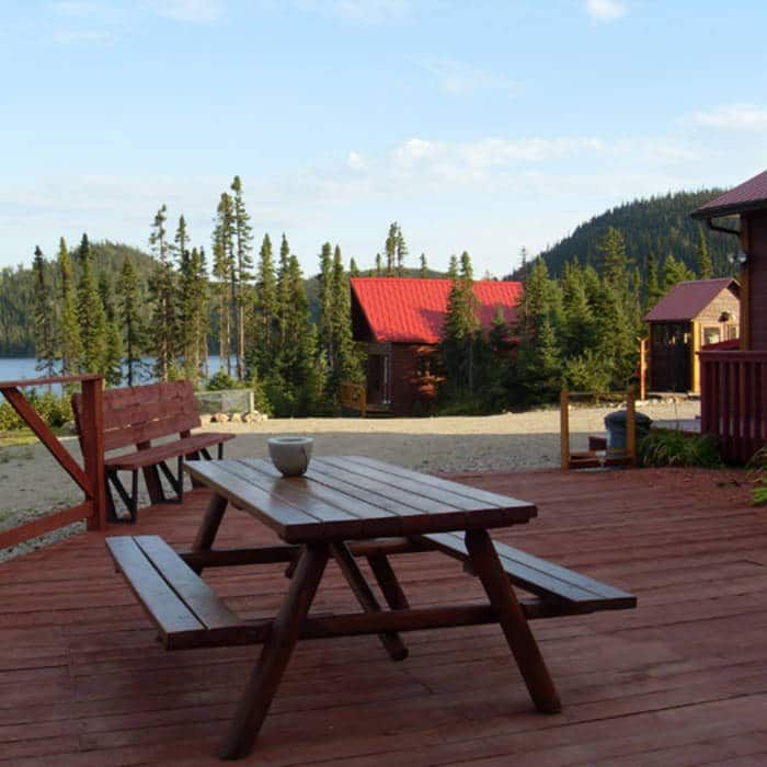 A picnic table on the deck offers a view of the cabins and the surrounding forest.