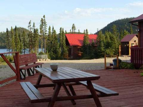 A picnic table on the deck offers a view of the cabins and the surrounding forest.