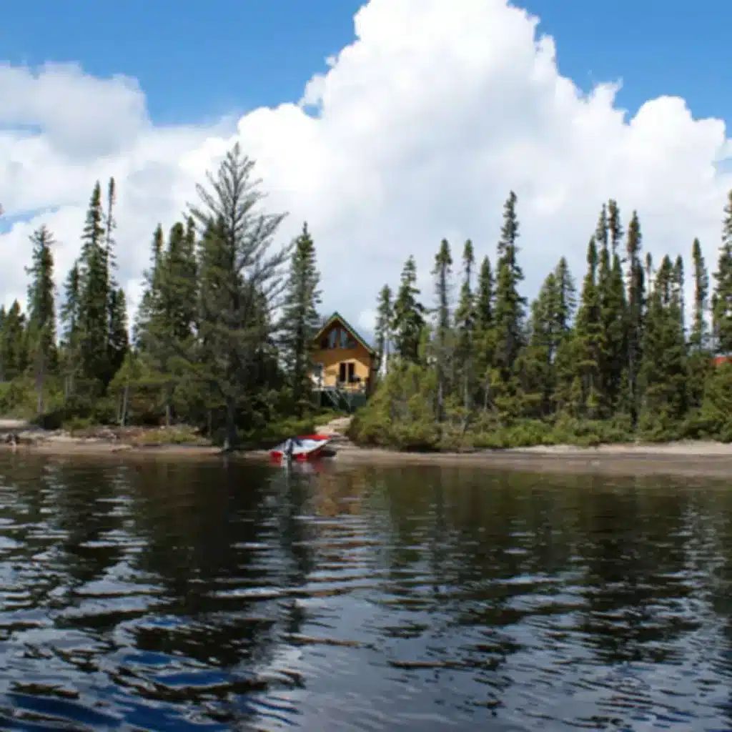Vue depuis le lac sur le chalet Point 2 entouré de forêt.