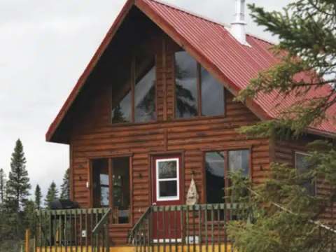 Vue extérieure du chalet en bois avec toit rouge et terrasse en façade.