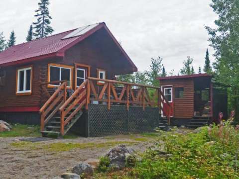 Vue extérieure du chalet Point 3 avec sa grande galerie en bois et son toit rouge.