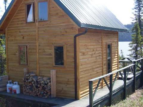 Side view of the wooden cottage with its deck and firewood storage.