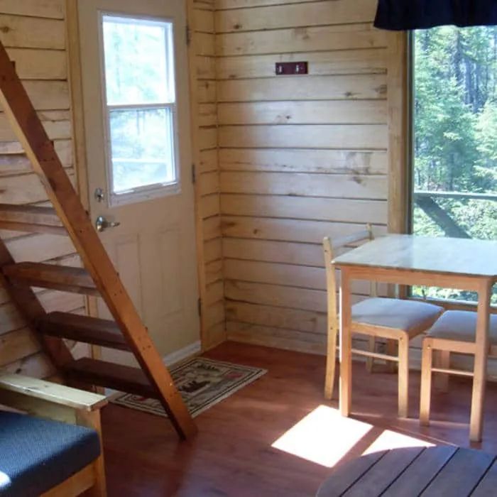 View of the cabin interior featuring a table, chairs, and access to the staircase.