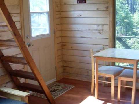 View of the cabin interior featuring a table, chairs, and access to the staircase.
