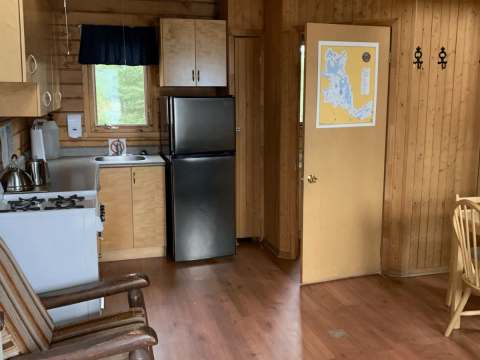 The functional kitchen of the cottage includes a refrigerator, a stove, and a dining table.