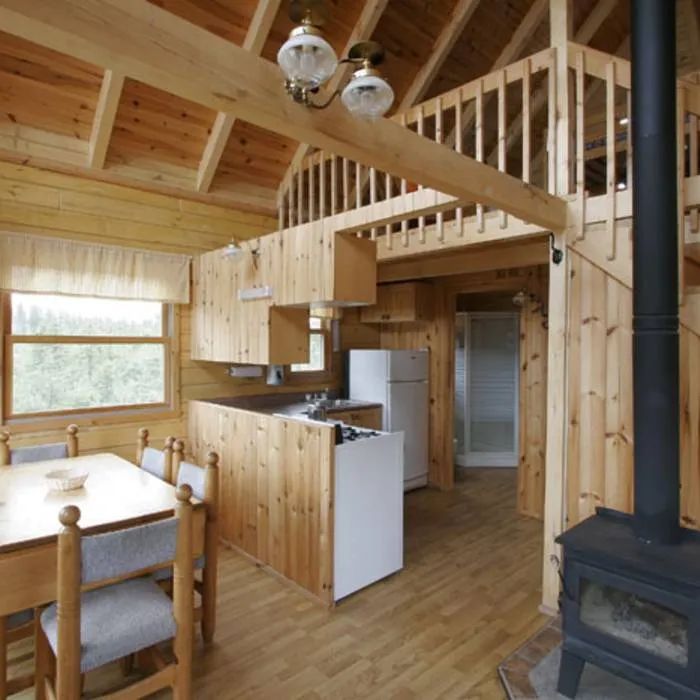 L'espace de vie principal comprend une cuisine fonctionnelle, une table à manger et un poêle à bois.