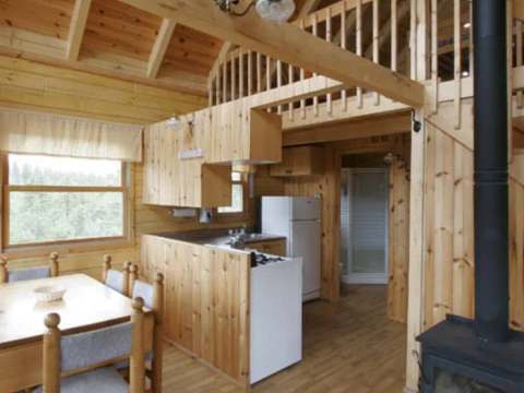 L'espace de vie principal comprend une cuisine fonctionnelle, une table à manger et un poêle à bois.