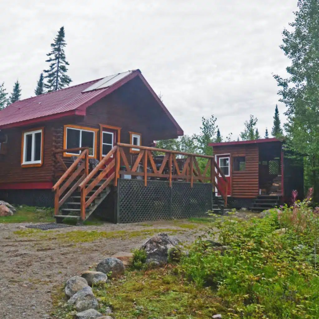 Vue extérieure du chalet Point 3 avec sa grande galerie en bois et son toit rouge.