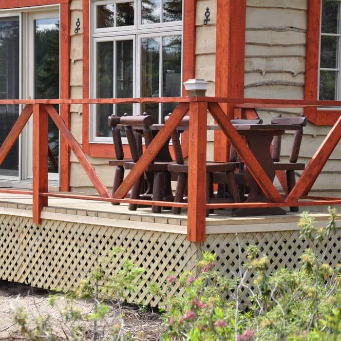 A table and chairs are set up on the wooden cabin deck.