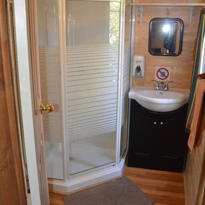 This cottage bathroom features a shower stall and a sink with a mirror.