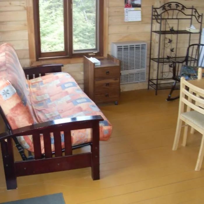 The cottage living area is furnished with a sofa bed and a dining table.