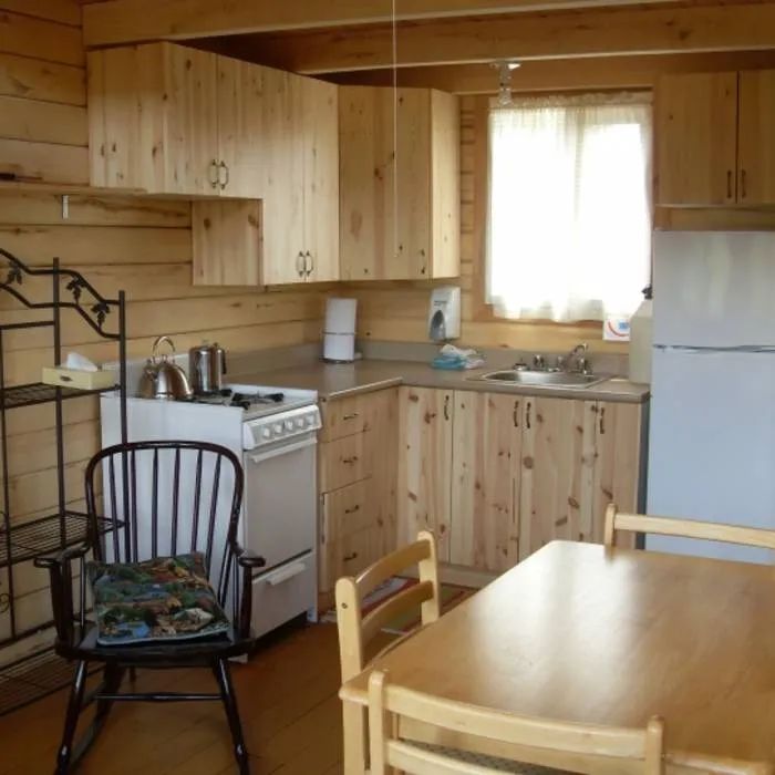 The cottage's functional kitchen includes a stove, a refrigerator, and a dining table.