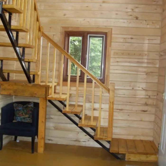 Interior view of the wooden and metal stairs leading to the upper floor of the cabin.
