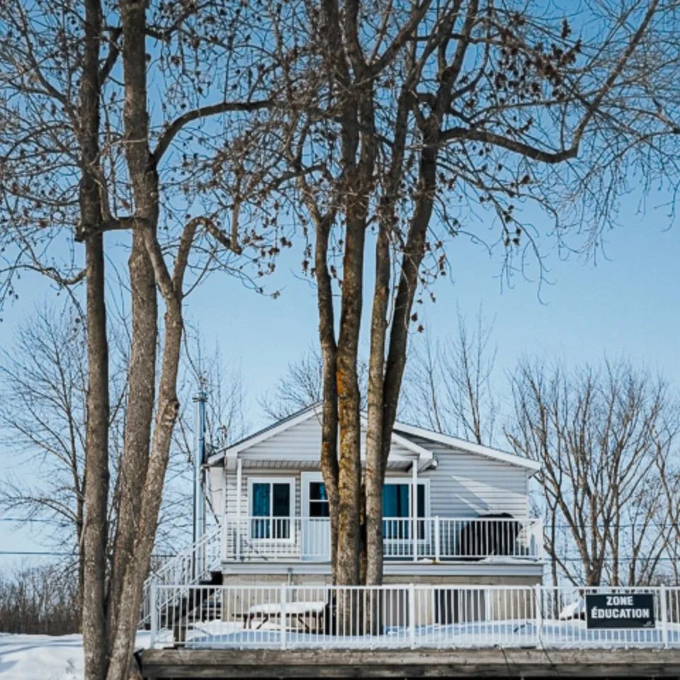 Le chalet Le Garrot se situe en forêt, entouré d'arbres matures en hiver.