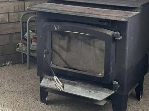 A cast iron wood stove is installed in the cabin's living room.