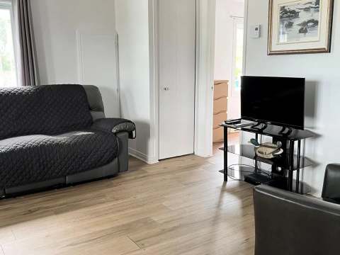 The cottage living room includes a comfortable sofa, an armchair, and a television.