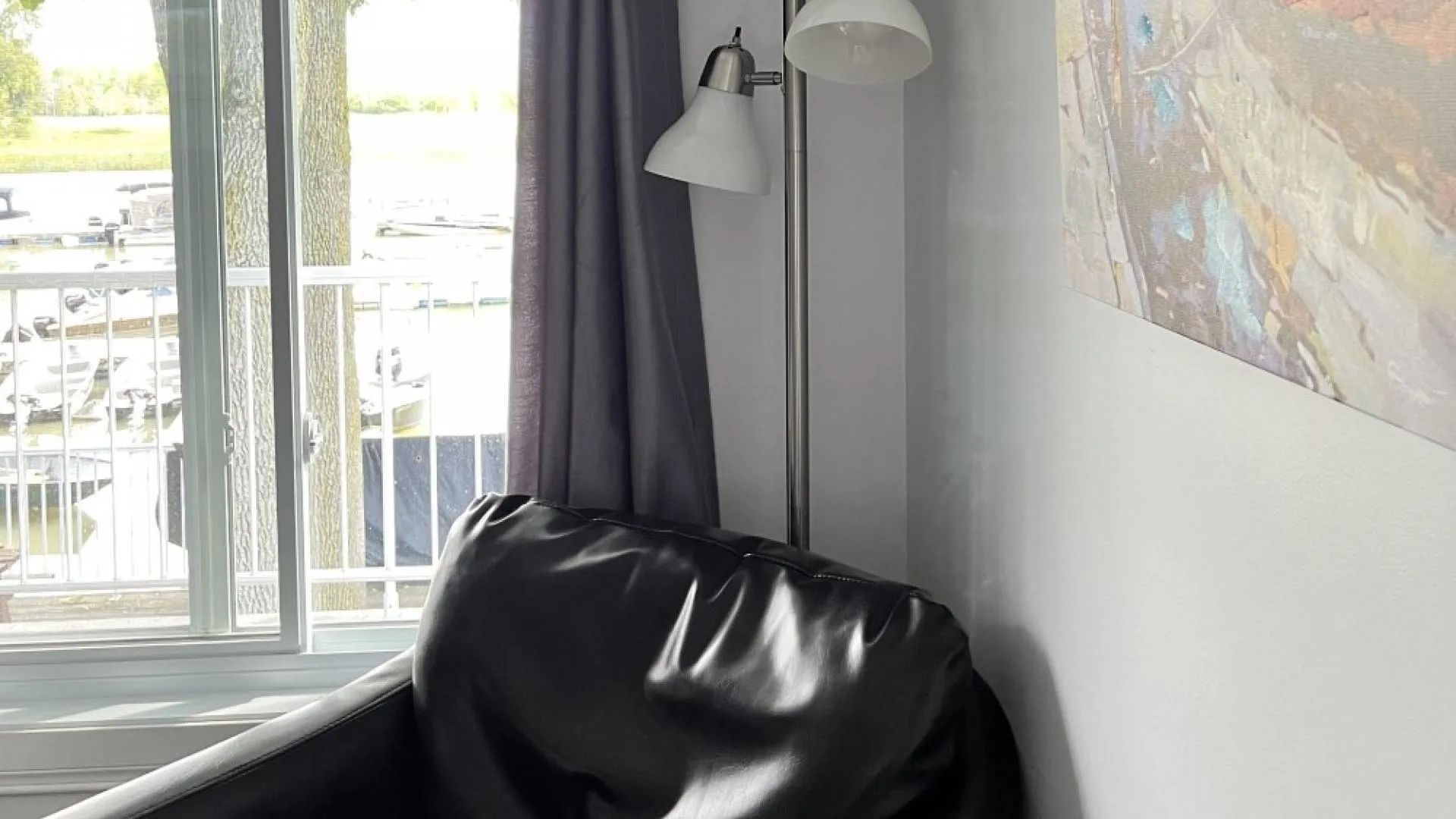 A comfortable armchair near the window with a view of the dock and boats.