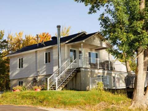 Le Garrot cottage features an outdoor balcony and stairs leading to the main level.