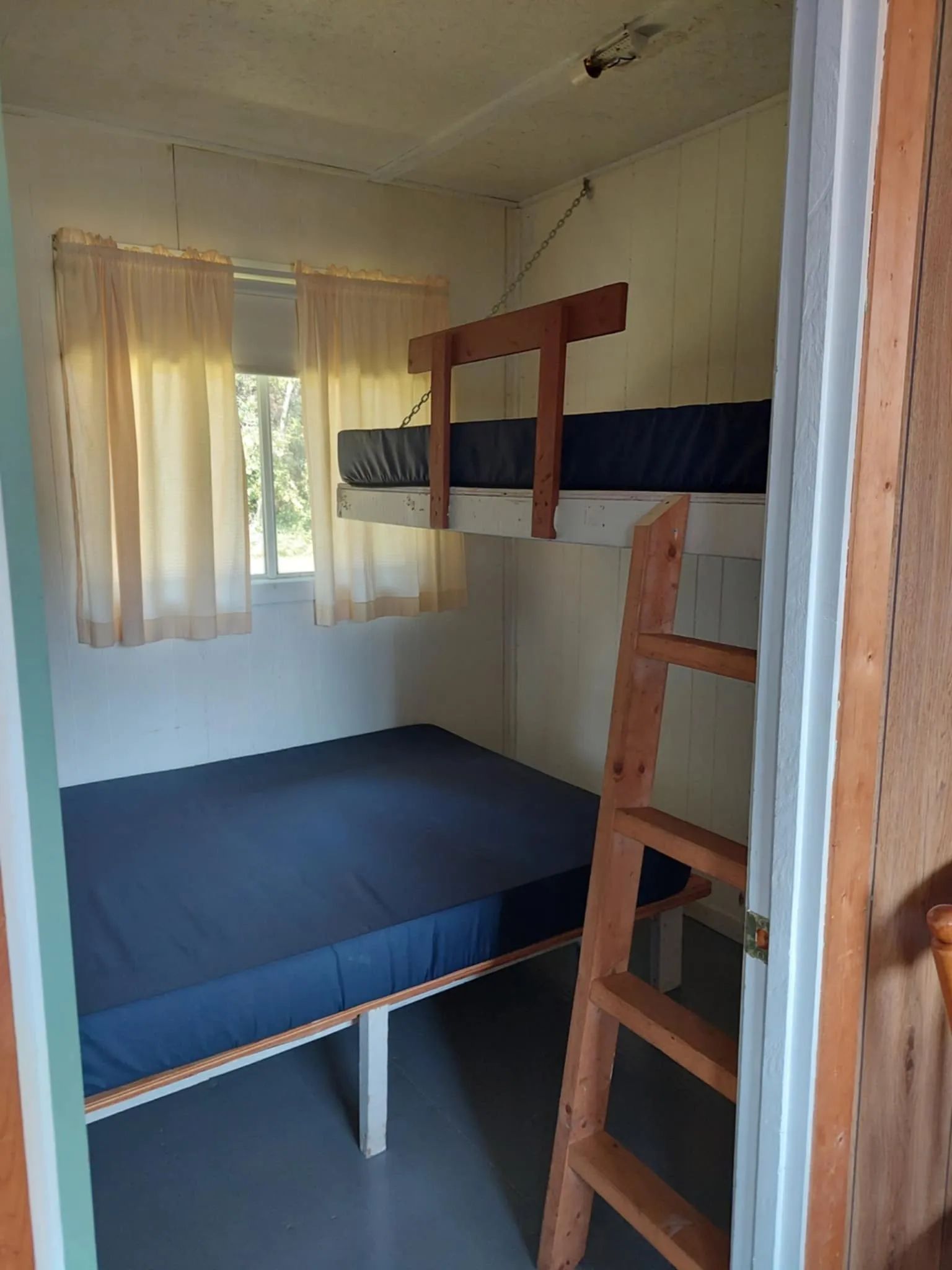 This cabin bedroom features a bunk bed with a single mattress on top and a double on the bottom.