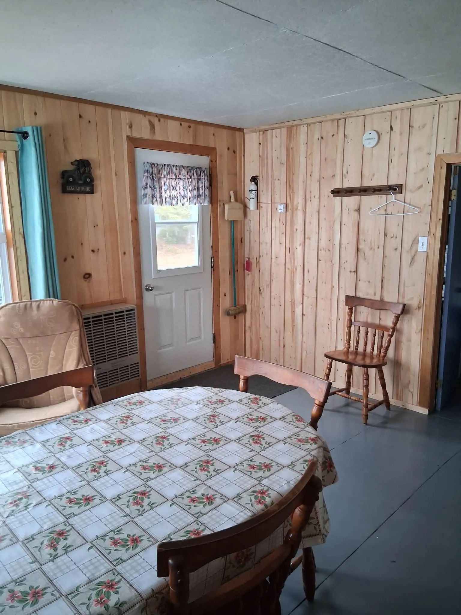 The dining area of Le Huard cabin features a round table and wooden chairs.