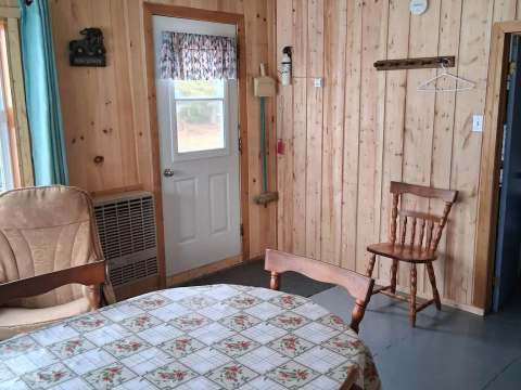 The dining area of Le Huard cabin features a round table and wooden chairs.