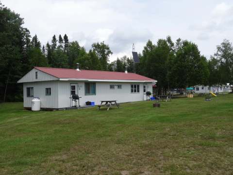 Exterior view of the cabin featuring picnic tables and barbecues in front of the entrances.