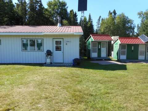 Exterior view of the main cabin and smaller adjacent units with green spaces.
