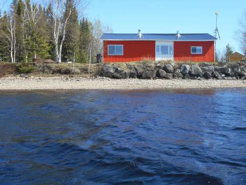 The Le Papillon cabin is located along the water with a distinctive red exterior.