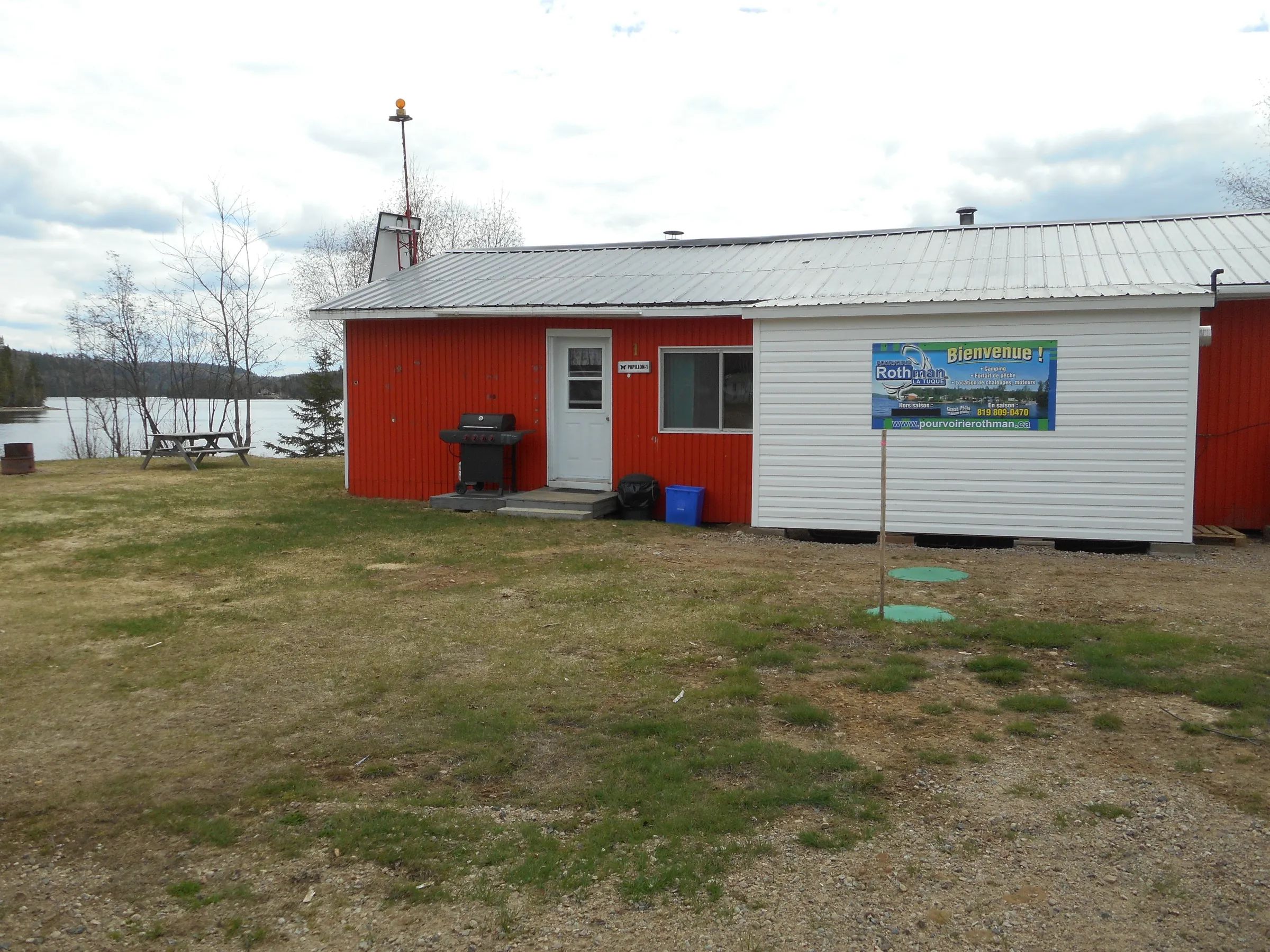 Exterior view of the Papillon cottage with its barbecue and a picnic table near the lake.