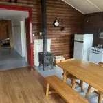 La cuisine et la salle à manger du chalet avec poêle à bois et murs en bois rond.