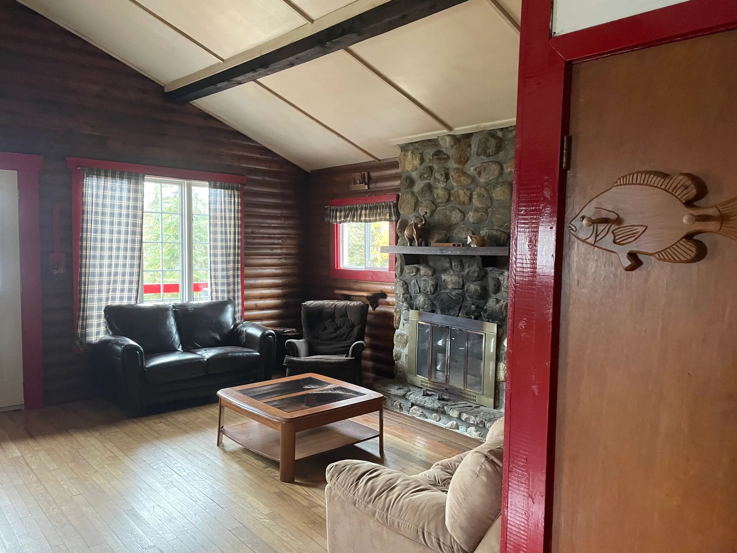 Le salon chaleureux du chalet Le Campagnard avec son foyer en pierre et ses murs en bois.