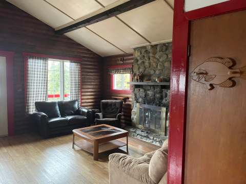 Le salon chaleureux du chalet Le Campagnard avec son foyer en pierre et ses murs en bois.