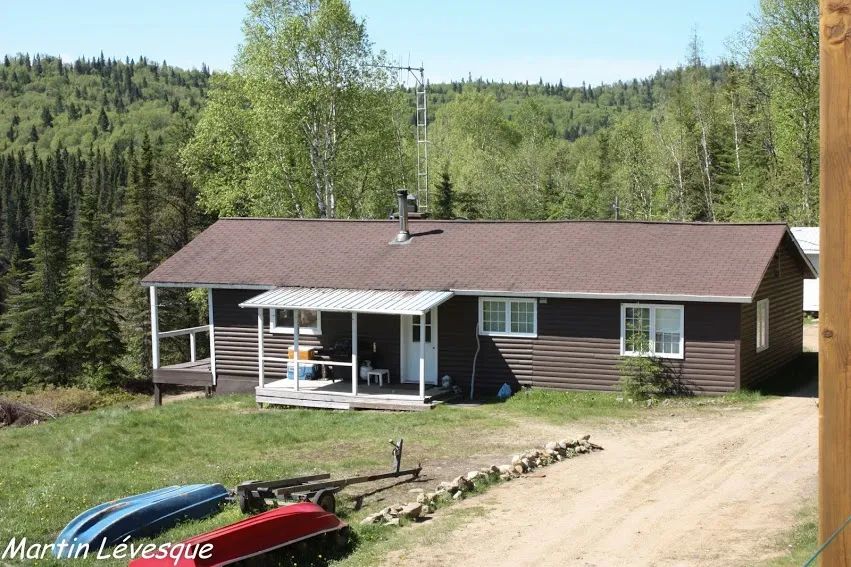 Le chalet campagnard avec sa véranda extérieure et son accès au terrain boisé.