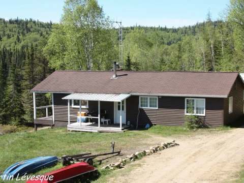 Le chalet campagnard avec sa véranda extérieure et son accès au terrain boisé.