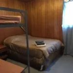 Cette chambre rustique comprend un lit double et un lit superposé avec des murs en bois.