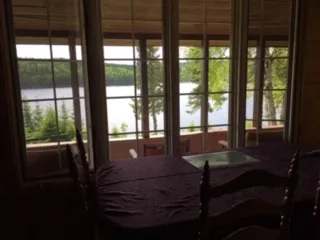 La salle à manger du chalet offre une vue directe sur le lac et la forêt environnante.