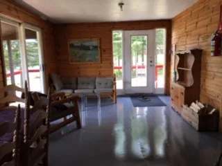 Le salon du chalet Le Canot offre un espace de détente chaleureux avec ses murs en bois naturel.