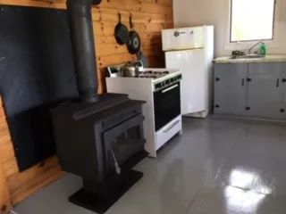 La cuisine du chalet comprend un poêle à bois, une cuisinière et un réfrigérateur.