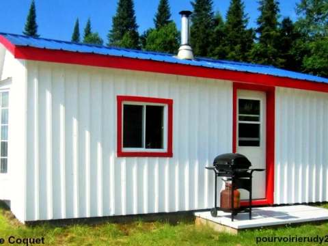 Le chalet Le Coquet possède un revêtement blanc avec des finitions rouges et un barbecue extérieur.