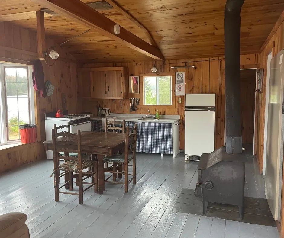 L'aire ouverte du chalet comprend une cuisine équipée, un coin repas et un poêle à bois.