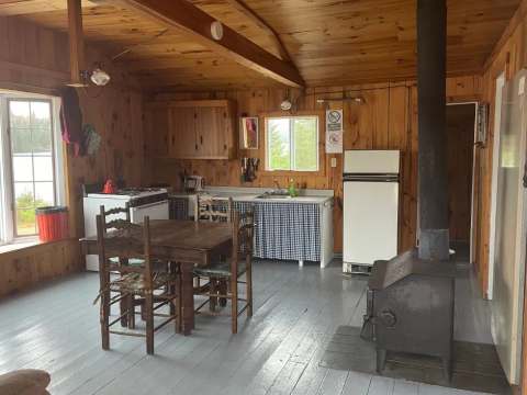 L'aire ouverte du chalet comprend une cuisine équipée, un coin repas et un poêle à bois.