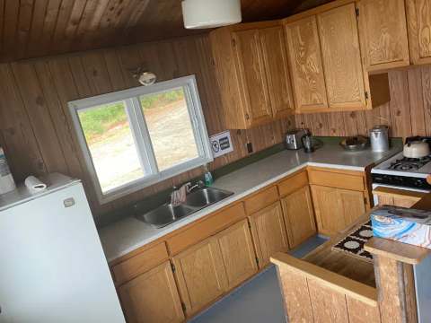 La cuisine fonctionnelle du chalet Le Familial dispose d'armoires en bois et d'une cuisinière.