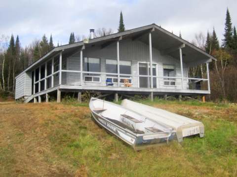 Le chalet Familial avec sa vaste galerie donnant sur le terrain et ses embarcations.