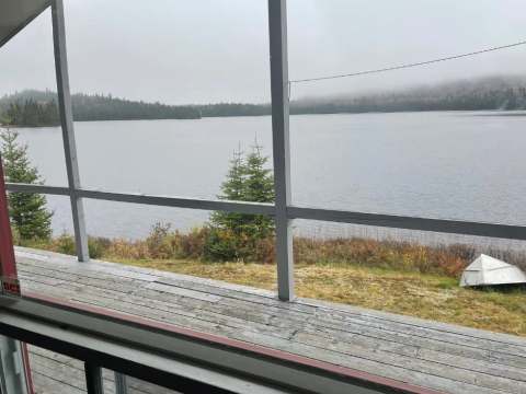 Vue sur le lac et la forêt depuis la galerie grillagée du chalet Le Familial.