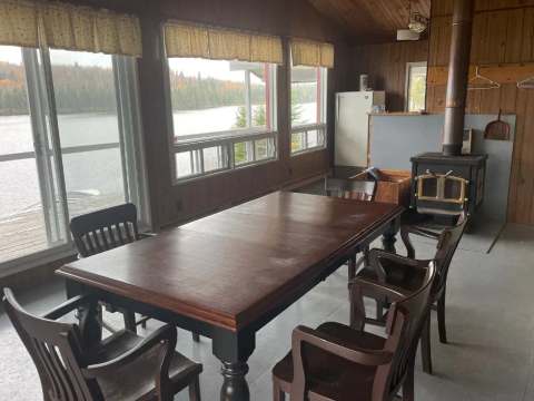 La salle à manger du chalet Le Familial avec vue sur le lac et poêle à bois.