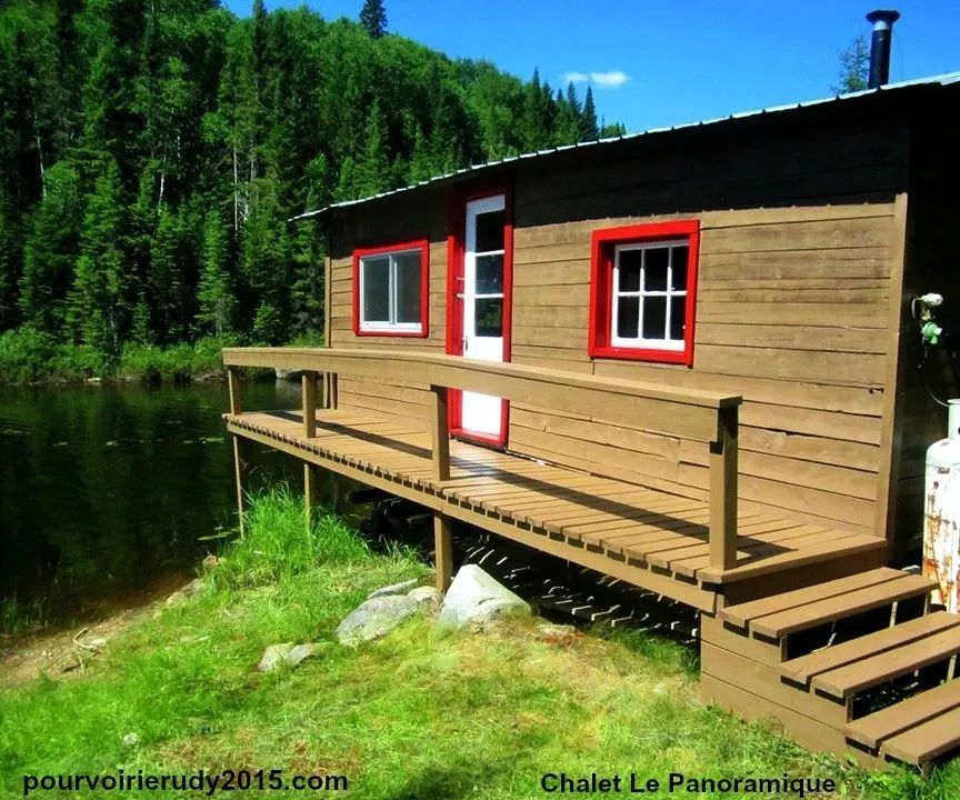 Le chalet Le Panoramique avec sa galerie en bordure de lac et ses fenêtres aux cadres rouges.