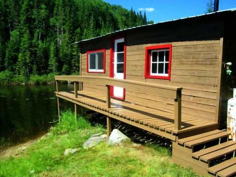 Le chalet Le Panoramique avec sa galerie en bordure de lac et ses fenêtres aux cadres rouges.